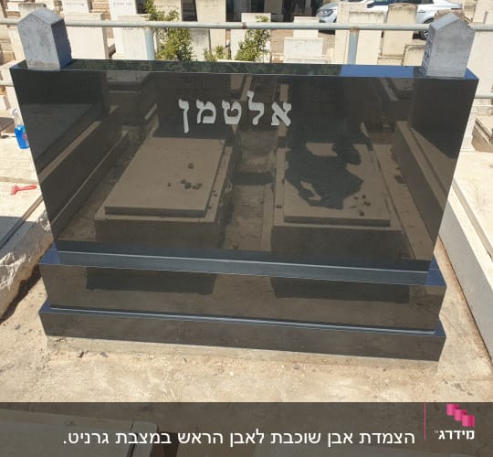 מצבה שחורה עם כיתוב בעברית בבית קברות